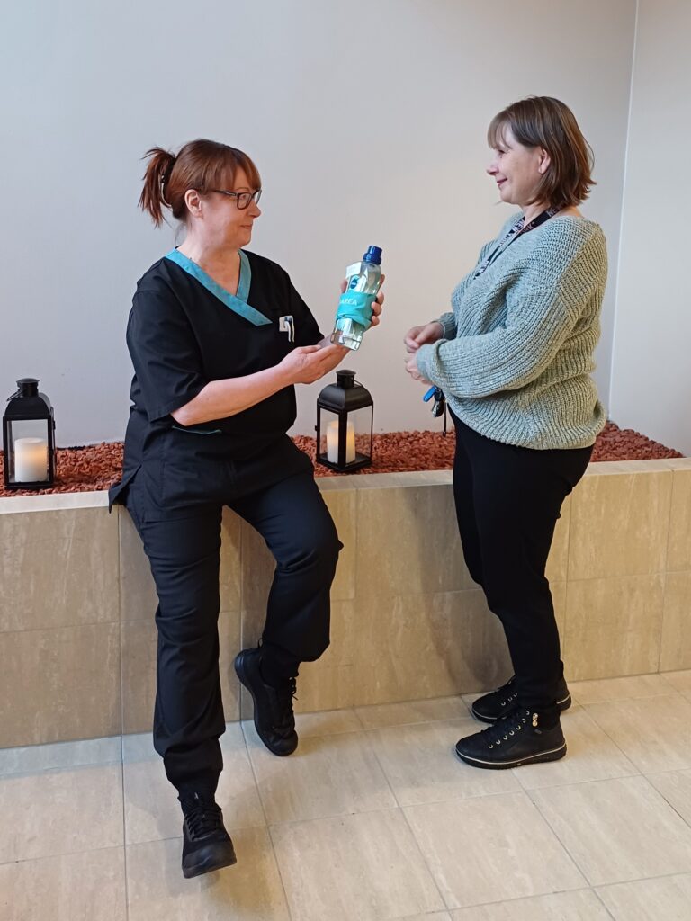 Palveluesihenkilö Sari Mäkitalo on ojentanut Anu Kinnuselle muistamisen. Anu katsoo tutteita.